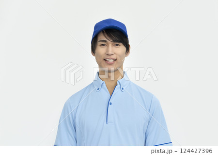 カメラ目線で笑顔の青いプロシャツを着た若い男性　作業員・施設スタッフイメージ 124427396
