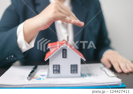 Home insurance concept. Homeowner entrusted the concept of protecting their property to the insurance agent's hand, ensuring their house and finances were secured through a mortgage insurance plan 124427411