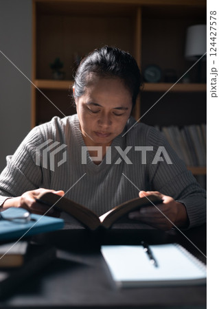 Woman with Bible in her hand, faith in God strengthened by holy words of book, found solace and inspiration through prayer in her Christian religion. bible, woman, book, religion, christian, holy. 124427578