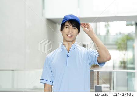 カメラ目線で笑顔の青いポロシャツを着た若い男性　作業員・施設スタッフイメージ 124427630