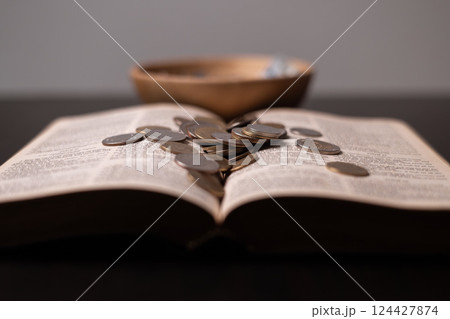 Christian finance principles tithing is seen as giving back to God as mentioned in the Bible where believers offer portion of their money gift of gratitude. tithe, coin, bible, christian, giving. 124427874