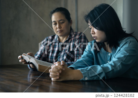 Hands clasped in prayer, Christians express their faith in God and worship Jesus Christ in the church, finding guidance and solace in the teachings of the Bible and their religious beliefs. 124428102