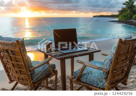 Laptop on the beach table. Place of work of a hermit freelancer. A solitary freelancer finds solace in the sand, working by the sea. 124429256