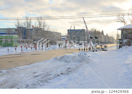 A snowy winter scene at a railway crossing with beautiful buildings in a serene setting A snowy winter scene at a railway crossing with beautiful buildings in a serene setting 124429368