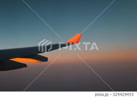 A Majestic Airplane Wing Casts a Silhouette Against a Stunning Sunset Sky Full of Colors 124429453