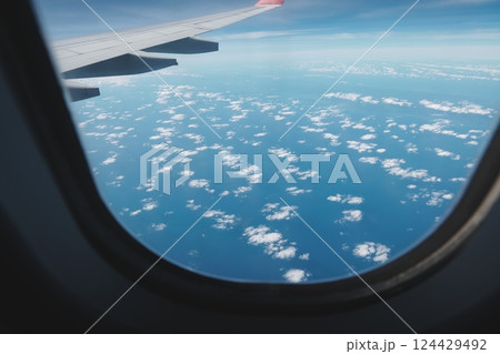 An aerial view of beautiful clouds above the vast blue ocean from an airplane window An aerial view of beautiful clouds above the vast blue ocean from an airplane window 124429492