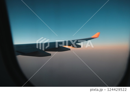 An Airplane Wing Silhouette Set Against a Beautifully Colorful Sky at Dusk During Sunset 124429522