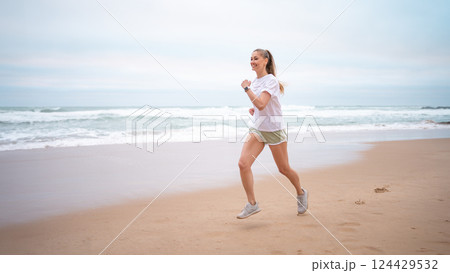 Sporty woman jogging on wet seashore at beach Sporty woman jogging on wet seashore at beach 124429532