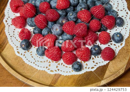 A Beautiful Arrangement of Fresh Berries on a Delicate Lace Doily A Vibrant Display 124429753