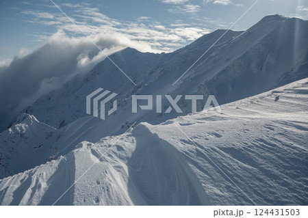 雪煙舞う山肌 険しい稜線の雪山 3月の雪山を登山 雪煙舞う山肌 険しい稜線の雪山 3月の雪山を登山 124431503