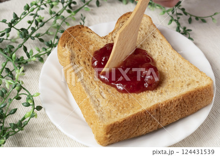 瓶詰めのいちごジャムをトーストした食パンに塗 124431539