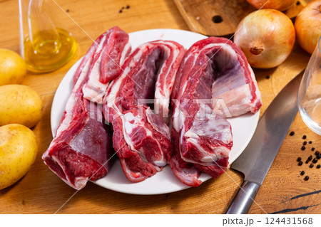 Raw beef ribs on board, potato tubers and whole onions 124431568