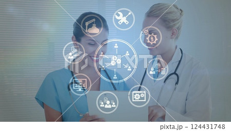 Image of business icons over caucasian female doctors talking 124431748