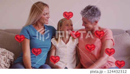 Red heart balloons image over three smiling people sitting on couch 124432312