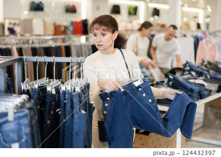 Middle-aged woman choosing blue jeans in clothing store 124432397