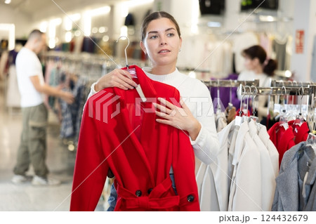 Young girl choosing unicolorous coat in clothing shop 124432679