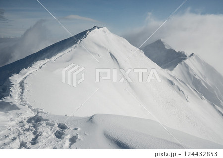 雪煙舞う山肌　険しい稜線の雪山　3月の雪山を登山 124432853