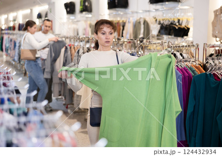 Middle-aged woman choosing nice cardigan in clothing store 124432934
