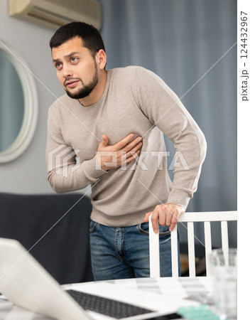Man experiencing chest pain after working long hours on laptop 124432967