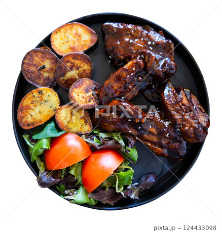 Pork ribs fried to dark crust and side dish of fried potatoes and handful of fresh vegetables 124433098