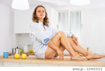 Beautiful young girl in shirt sitting on table 124433151