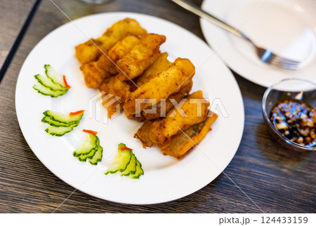 Pieces of eel fillet, fried to crispy crust, garnished with cucumber slices. 124433159