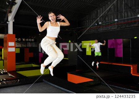 Cheerful young girl jumping in indoor trampoline arena 124433235