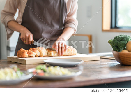 フランスパンを切る女性の手元 124433405