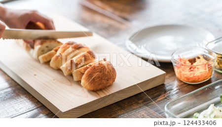 フランスパンを切る女性の手元 124433406