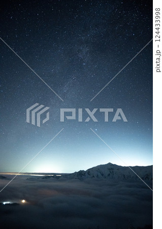 晴天の下、西穂高岳稜線から岐阜県の夜景と北アルプスを眺める　軌跡で見る星空 124433998