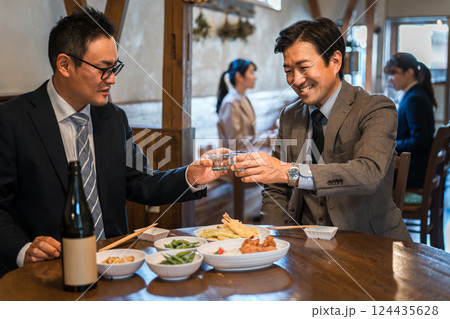 居酒屋・飲み屋で部下と楽しくお酒を飲むビジネスマンの男性 居酒屋・飲み屋で部下と楽しくお酒を飲むビジネスマンの男性 124435628