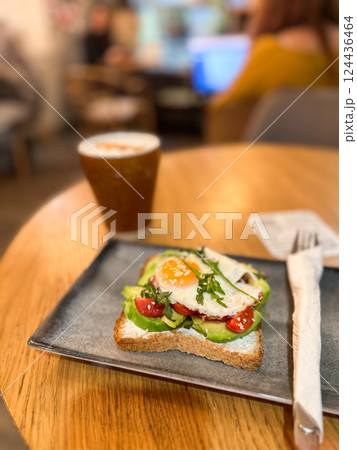 Avocado toast with egg served on a ceramic plate in cozy cafe. Healthy breakfast and balanced nutrition in a lifestyle setting. Avocado toast with egg served on a ceramic plate in cozy cafe. Healthy breakfast and balanced nutrition in a lifestyle setting. 124436464