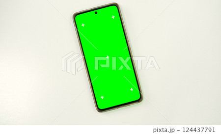 Mobile phone with green screen lies on white surface. Mobile phone mockup. Social media advertising concept, trading platforms. Smartphone with chromakey. Close-up. Plenty of space for your text. 124437791