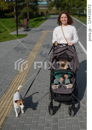 Caucasian woman walks in the park with her one-year-old son and Jack Russell Terrier dog.  124438072