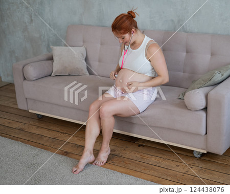 A pregnant woman listens to her baby's pulse using a phonendoscope. A pregnant woman listens to her baby's pulse using a phonendoscope. 124438076