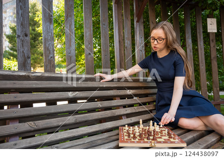 Caucasian woman playing chess outdoors. 124438097