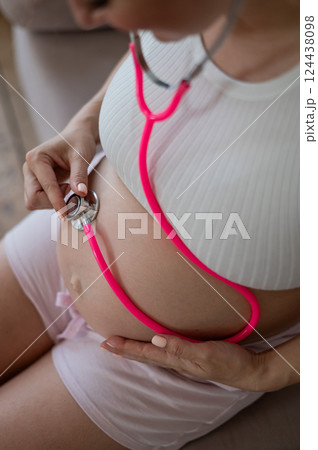 A pregnant woman listens to her baby's pulse using a phonendoscope. 124438098