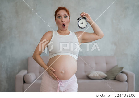 Caucasian pregnant woman holding alarm clock waiting for delivery. Caucasian pregnant woman holding alarm clock waiting for delivery. 124438100