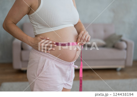 Pregnant woman measuring her belly.  124438194