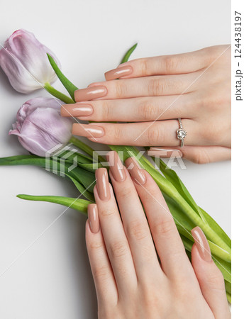 Woman showing nude manicure and purple tulips on white background 124438197