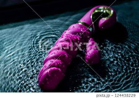 Pink ribbed vibrator in water. Circles on water around sex toy.  124438229