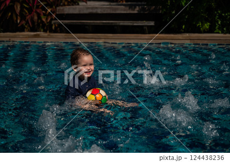 Caucasian one year old boy playing ball in swimming pool. Caucasian one year old boy playing ball in swimming pool. 124438236