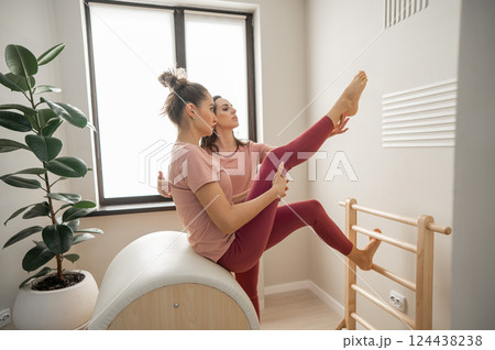A trainer adjusts woman on a Ladder Barrel. Personal training.  124438238