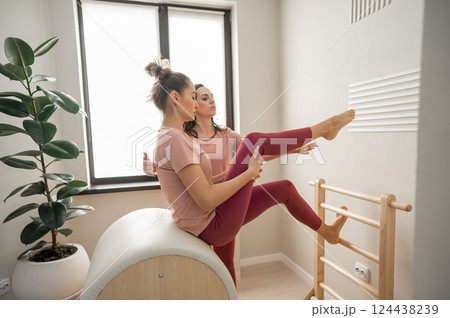 A trainer adjusts woman on a Ladder Barrel. Personal training. A trainer adjusts woman on a Ladder Barrel. Personal training. 124438239