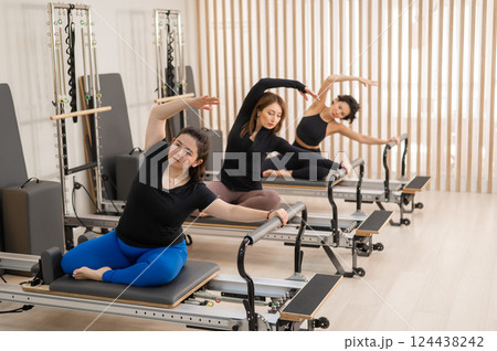 Three Asian women doing Pilates on a reformer.  124438242