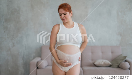Caucasian pregnant woman in adult diapers suffers from incontinence.  124438277