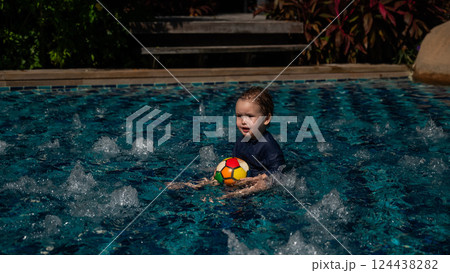 Caucasian one year old boy playing ball in swimming pool. Caucasian one year old boy playing ball in swimming pool. 124438282