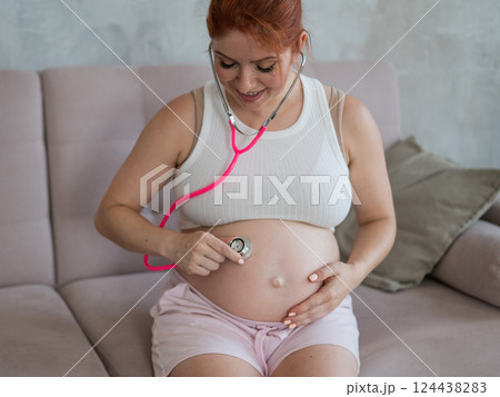 A pregnant woman listens to her baby's pulse using a phonendoscope. 124438283