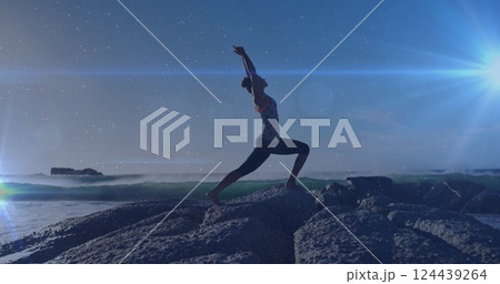 Image of light spots over biracial woman practicing yoga at beach Image of light spots over biracial woman practicing yoga at beach 124439264