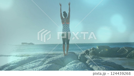 Image of light spots over biracial woman practicing yoga at beach Image of light spots over biracial woman practicing yoga at beach 124439268